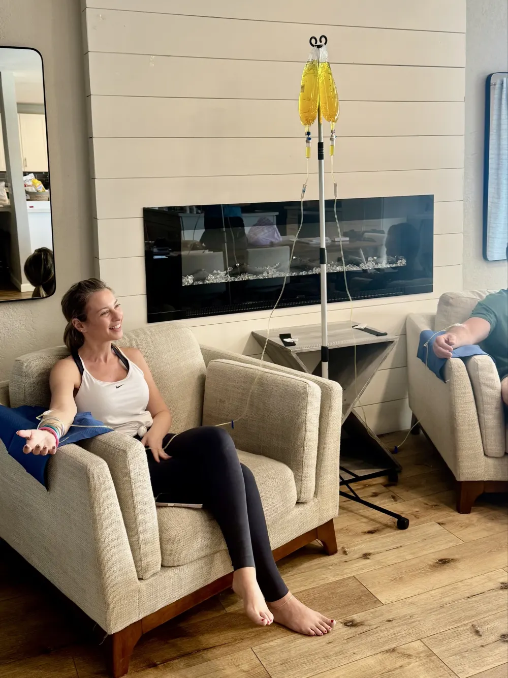 A smiling client relaxes on her couch at home during an IV drip